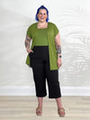 Miik model Kaitlin (5'9", xlarge) smiling wearing Miik's Evie short sleeve pocket cardigan in green moss with a tank top in the same colour and a capri pant in black #color_moss