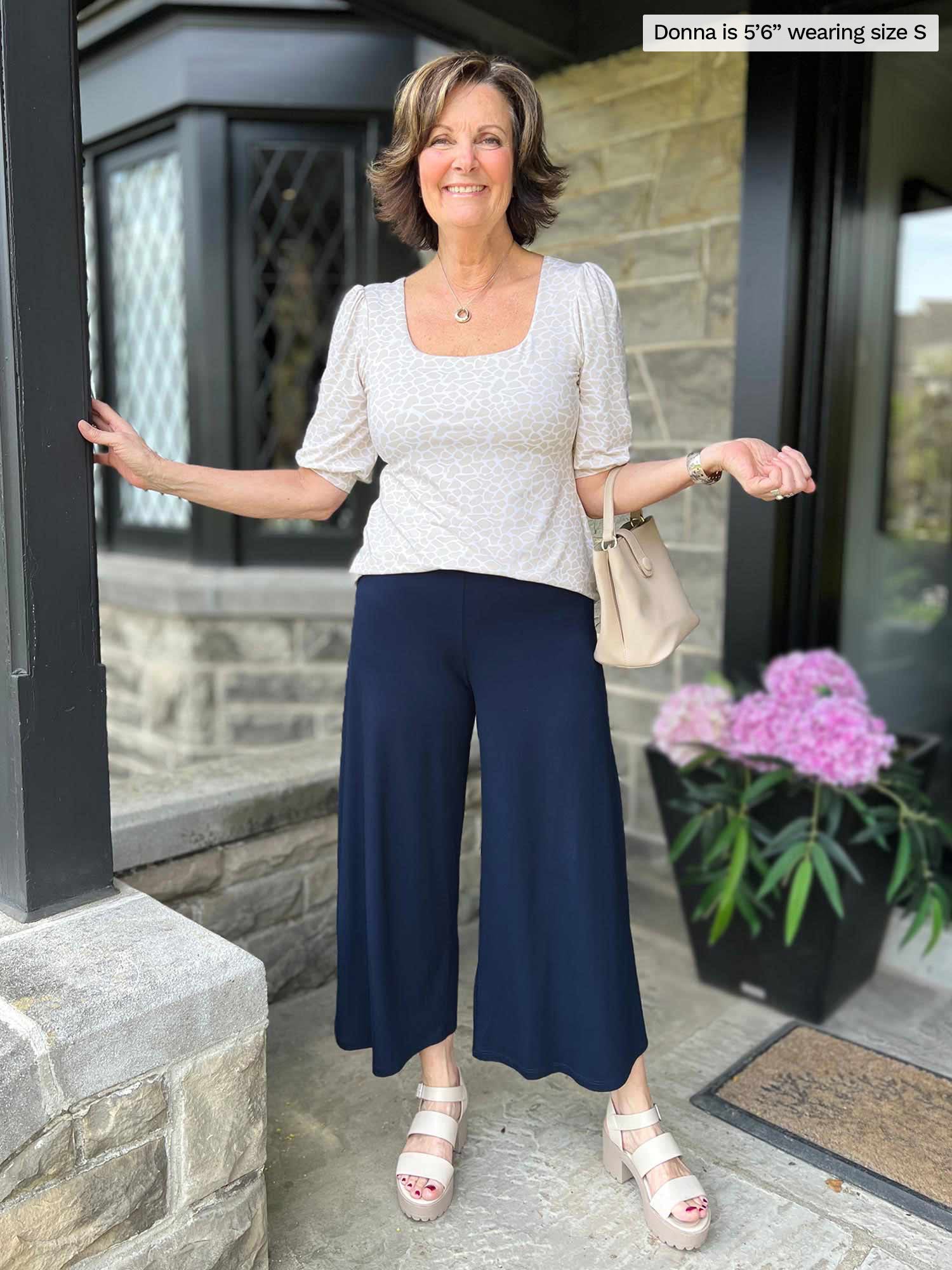 Miik founder Donna (five feet six, small) standing in front of a house smiling wearing a navy capri pant with Miik&