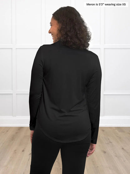 Miik model Meron (5’3”, xsmall) standing with her back towards the camera showing the back of Inna long sleeve button up shirt in black
