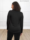 Miik model Meron (5’3”, xsmall) standing with her back towards the camera showing the back of Inna long sleeve button up shirt in black
#color_black