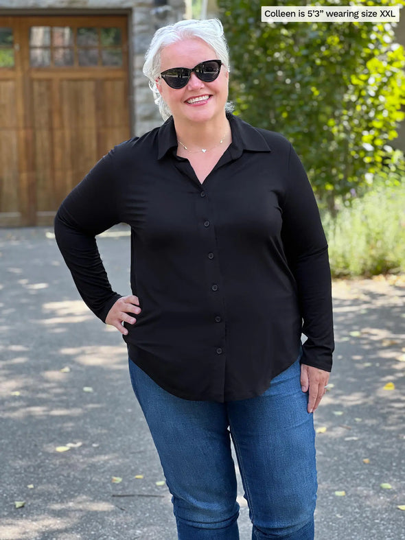 Miik model Colleen (5'3", xxlarge) smiling wearing Miik's Inna long sleeve button up shirt in black with jeans and sunglasses 
#color_black