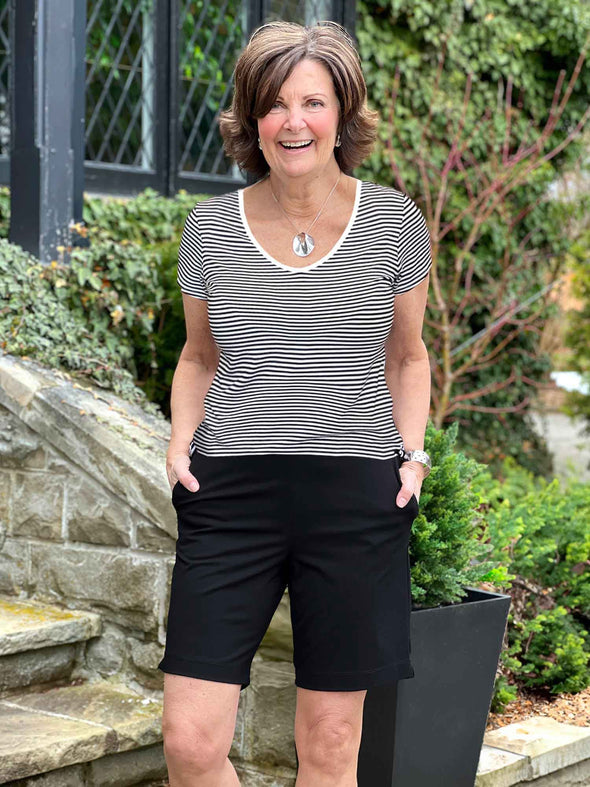 Miik founder Donna (5'6", small) laughing wearing a mini stripe black and white tee with Miik's Irelynn bermuda pocket short in black  #color_black