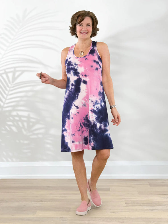 Miik founder Donna (5'6", small) smiling while standing in front of a white wall wearing Miik's Jackie french terry tank dress in northern lights tie dye with a pink sneakers #color_northern-lights 