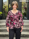 Miik model Jenna (5'9", small) smiling wearing Miik's Jayna v-neck 3/4 sleeve top in midnight floral with a black pants 