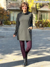 Miik founder Donna (5'6", small) smiling wearing a port legging along with Miik's Kaito cowl neck pocket tunic in charcoal #color_charcoal 