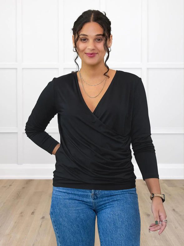 Miik model Meron (5’3”, xsmall) wearing Miik's Kathryn ruched faux-wrap blouse in black with blue jeans #color_black