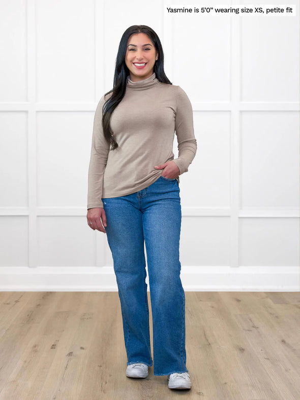 Miik model Yasmine (5'0", xsmall, petite) smiling wearing Miik's Kerry turtleneck top in mushroom melange, petite fit, with jeans #color_mushroom-melange