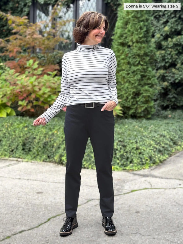 Miik founder Donna (5'6", small) smiling wearing Miik's Kerry turtleneck top in newport stripe with a black pant and belt #color_newport-stripe