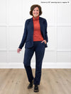 Miik founder Donna (5'6", small) smiling while standing in front of a white wall wearing a navy dress pant along with Miik's Kerry turtleneck top in paprika melange, regular fit, a a navy blazer #color_paprika-melange 