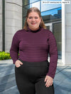 Miik model Bri (5'5", xlarge) smiling wearing Miik's Kerry turtleneck top in porto stripe, regular fit, with a black dress pant #color_porto-stripe