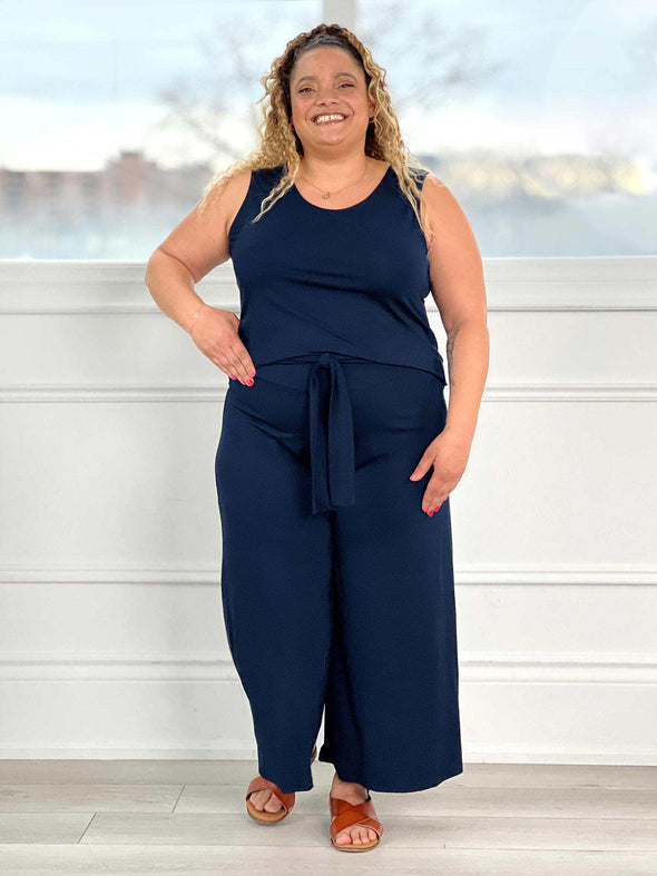 Miik model Carley (five feet two, size double extra large) smiling wearing Miik's Kimmay open-back capri jumpsuit in navy #color_navy