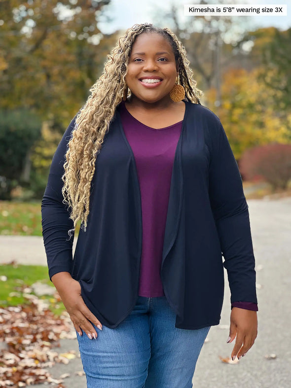 Miik model Kimesha (5'8", 3x) smiling wearing Miik's Kita long sleeve v-neck top in port with a waterfall cardigan in navy and jeans #color_port 