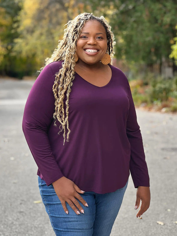 Miik model Kimesha smiling wearing Miik's Kita long sleeve v-neck top in port with jeans #color_port