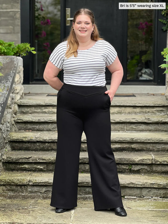 Miik model Bri (5'5", xlarge) smiling wearing Miik's Kiva high waisted wide leg ponte pant with pockets in black with a striped tee #color_black