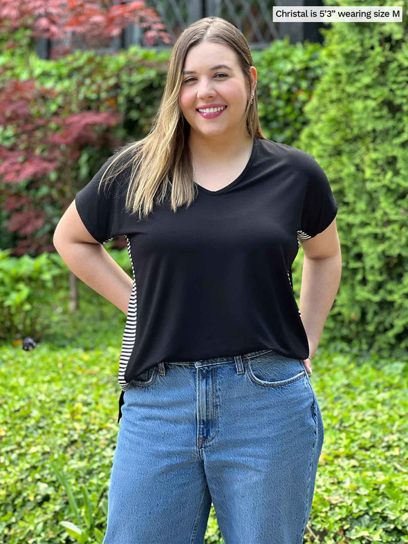 Miik model Christal (5'3", medium) smiling wearing Miik's Kylie striped side band top in black mini stripe tucked in with jeans
#color_black-mini-stripe