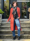 Miik founder Donna (5'6", small) smiling wearing Miik's Larissa duster cardigan with pockets in paprika melange, regular fit, with a charcoal tee, ripped jeans and a orange/black scarf #color_paprika-melange 