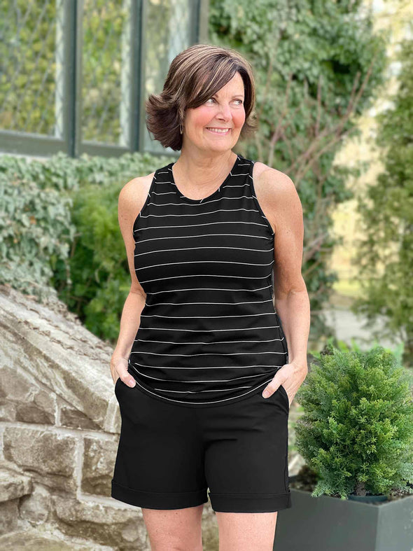 Woman standing in front of nature wearing Miik's Leland everyday dressy short in black with a black striped tank