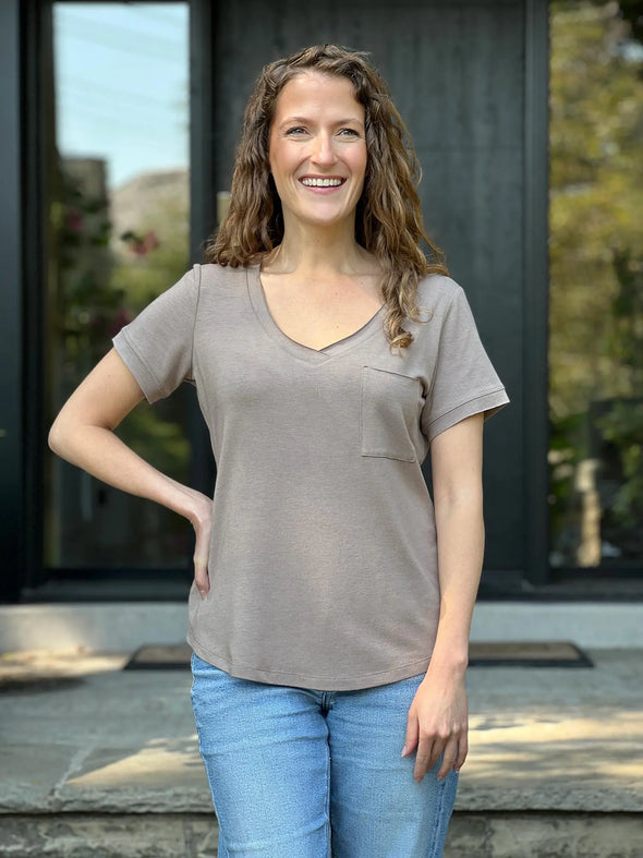 Miik model Lex (5'2", xsmall) smiling wearing Miik's Lex v-neck pocket tee in mushroom melange with jeans 
#color_mushroom-melange