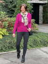 Miik founder Donna (5'6", small) smiling and looking away wearing Miik's Lisa2 high waisted legging in charcoal, regular fit, along with a bright pink sweater and a scarf #color_charcoal 