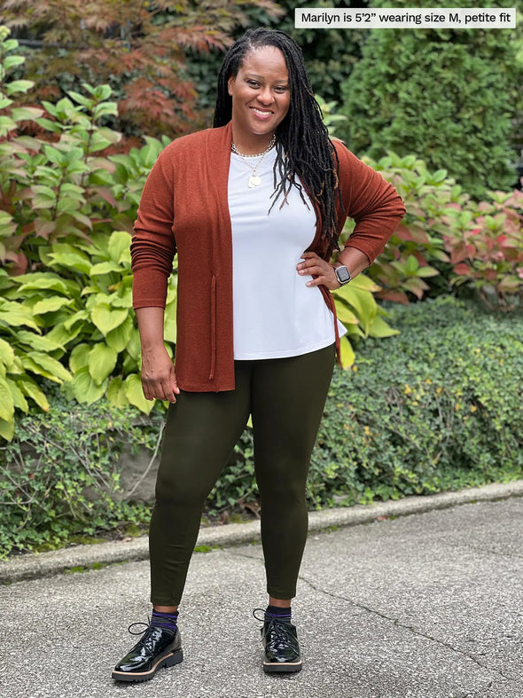 Miik model Marilyn (5'2", medium) smiling wearing Miik's Lisa2 high waisted legging in olive, petite fit, along with a white tank and a chestnut cardigan #color_olive