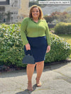 Miik model Carley (5'2", xxlarge) smiling wearing Miik's Lucia collared shirt in green moss with a pencil skirt in navy #color_moss