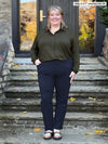 Miik model Kelly (5'7", 3x) smiling wearing Miik's Lucia collared shirt in olive with a navy dress pant #color_olive 