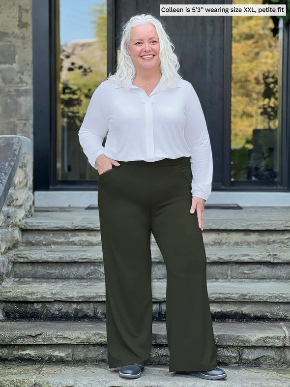 Miik model Colleen (5'3", xxlarge, petite) smiling wearing Miik's Lucia collared shirt in white, petite fit, tucked in a wide leg pants in green olive 
#color_white