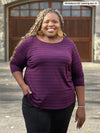 Miik model plus size Kimesha (5'8", 3x) smiling wearing Miik's Mahala boatneck 3/4 sleeve top in porto stripe with a black dress pant #color_porto-stripe 