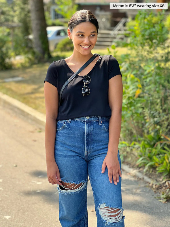 Miik model Meron (5'3", xsmall) smiling wearing Miik's Marianna reversible classic tee in black with a ripped jeans 
#color_black 