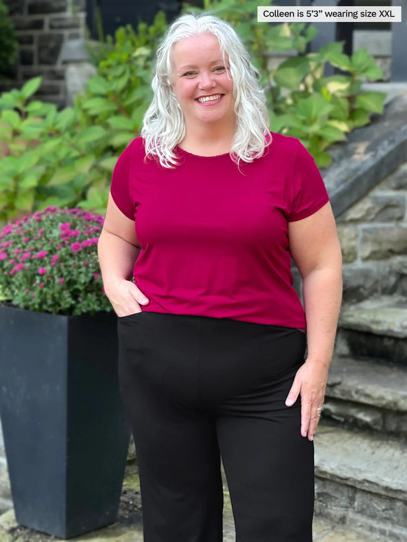 Miik model Colleen (5'3", xxlarge) smiling wearing Miik's Marianna reversible neckline classic tee in cerise with a black pant 
#color_cerise