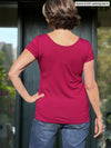 Miik founder Donna (5’6”, small) standing with her back towards the camera showing the back of Miik's Marianna reversible neckline classic tee in cerise and jeans 
#color_cerise 