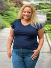 Miik model Carley (five feet two, xxlarge) smiling in front of a garden wearing Miik's Marianna reversible classic tee in navy and jeans 
#color_navy