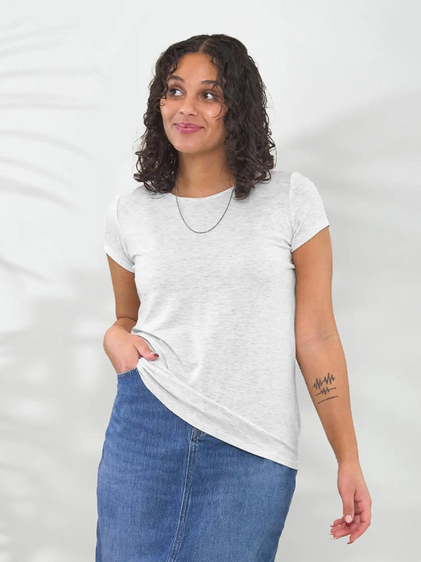 Miik model Meron (5'3", xsmall) smiling and looking away wearing Miik's Marianna reversible neckline classic tee in pearl melange with a maxi denim skirt