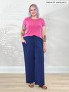 Miik model Kaitlin (5'9", xlarge) smiling wearing a wide leg lounge pant in marine blue along with Miik's Marianna reversible neckline classic tee in pretty in pink #color_pretty-in-pink