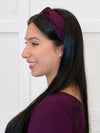 Miik model Yasmine smiling wearing Miik's Matana twist knot headband in port with a top in the same colour #color_port