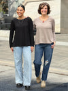 Miik model Meron and founder Donna standing next to each other both wearing Miik's Pippa reversible neckline long sleeve top with jeans. Meron is wearing in black while Donna is wearing in mushroom melange 