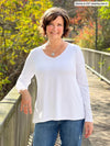 Miik founder Donna (5'6", small) smiling wearing jeans along with Miik's Pippa reversible neckline long sleeve top in white #color_white 