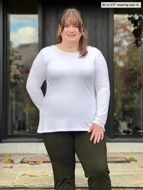 Miik model Bri (5'5", xlarge) smiling wearing Miik's Pippa reversible neckline long sleeve top in white with a olive colour dress pant #color_white 