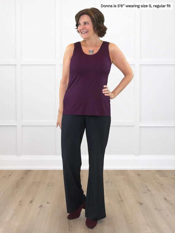 Miik founder Donna (5'6", small) smiling and looking away wearing Miik's Reed high waisted pant with pockets in black, regular fiit, with a tank top in port 
#color_black