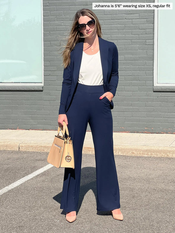 Miik model Jo (5'6", xsmall) smiling wearing Miik's Reed high waisted pant with pockets in navy, regular fit, along with a blazer in the same colour and a white tank top 
#color_navy