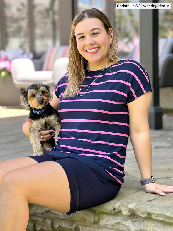 Woman sitting down with a dog wearing Miik's Rio reversible dolman tee in navy and pink stripe with shorts.