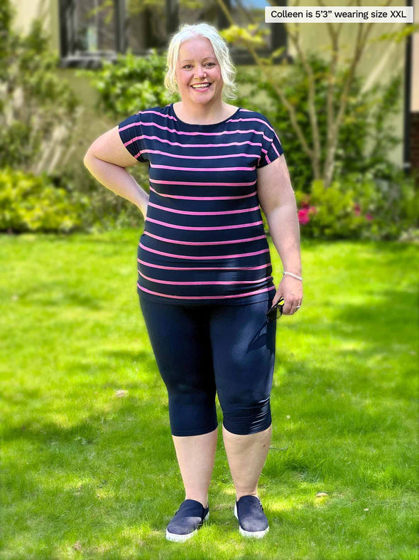 Woman standing in the garden wearing Miik's Rio reversible dolman tee in navy pink stripe with leggings.