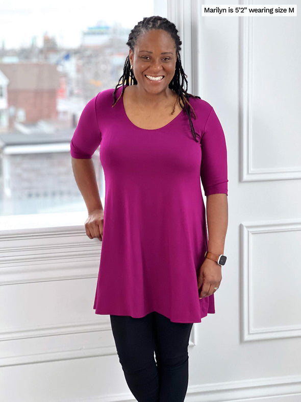 Woman standing wearing Miik's Rocelle half-sleeve scoop neck tunic in ruby pink with leggings