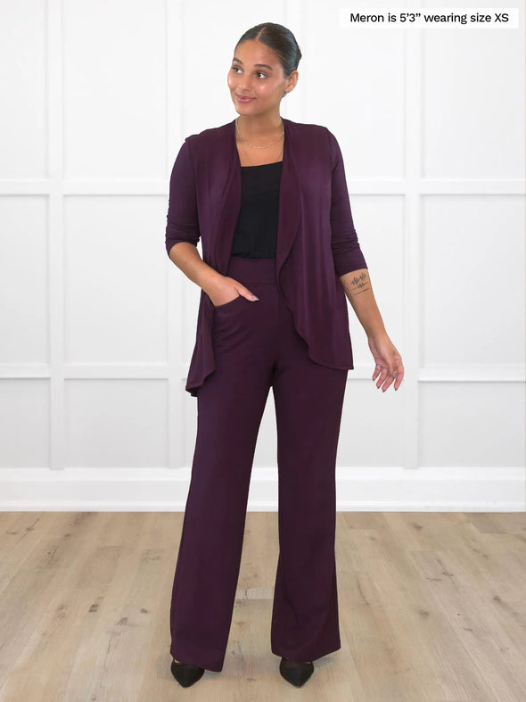 Miik model Meron (5'3", xsmall) smiling and looking away wearing Miik's Rory waterfall cardigan in port with a high waisted pant in the same colour and a black tank 
#color_port