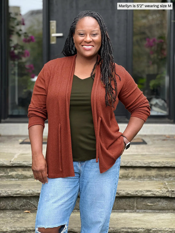 Miik model Marilyn (5'2", medium) smiling wearing Miik's Sadira tie waist sweater cardigan in chestnut with a ripped jeans and a olive v-neck tee #color_chestnut 