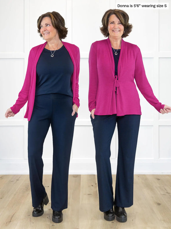 Miik founder Donna (5'6", small) smiling while standing in front of a white wall showing the two ways of wearing the new Miik's Sadira tie waist sweater cardigan in lipstick. In the left, Donna is wearing the cardigan open and on the right she is wearing it tied #color_lipstick