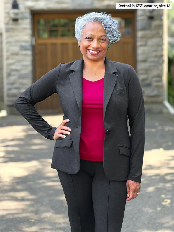 Miik model Keethai (5'5", medium) smiling wearing Miik's Shandra reversible neckline tank top in cerise along with a blazer and dress pant in charcoal 
#color_cerise 