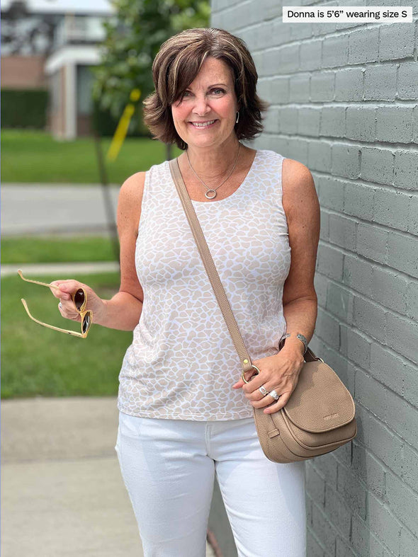 Woman standing next to a building wearing Miik's Shandra reversible tank top in cobblestone print and white pants.