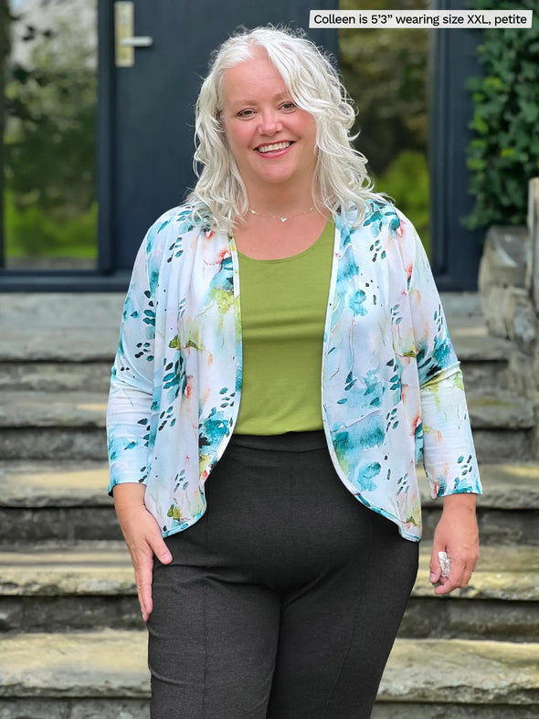 Miik model Colleen (5'2", xxlarge, petite) smiling wearing Miik's Shandra reversible tank top in moss in petite fit along with a cropped cardigan in water lily print and a charcoal dress pant 
#color_moss 