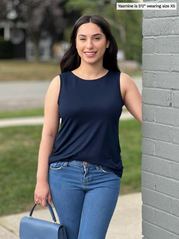 Woman standing next to a building wearing Miik's Shandra reversible tank top in navy with jeans.